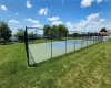 View of tennis court with a yard