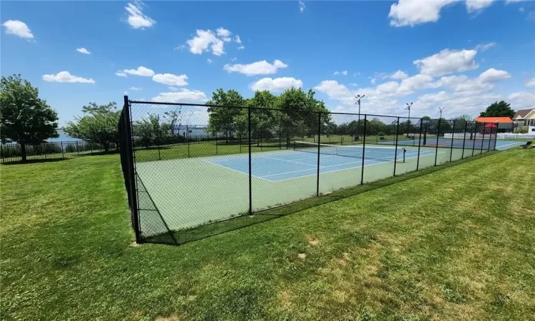 View of tennis court with a yard