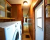 Laundry area with wood-type flooring, a textured ceiling, wooden walls, and independent washer and dryer