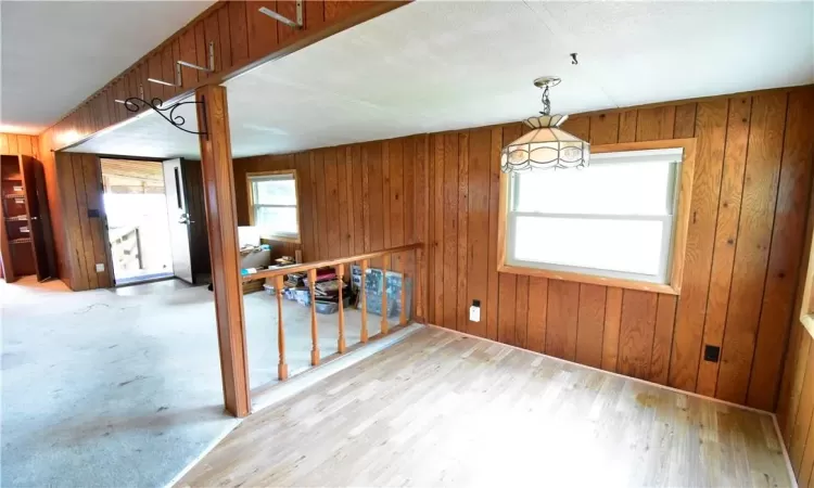 Unfurnished dining area with wooden walls and light hardwood / wood-style flooring