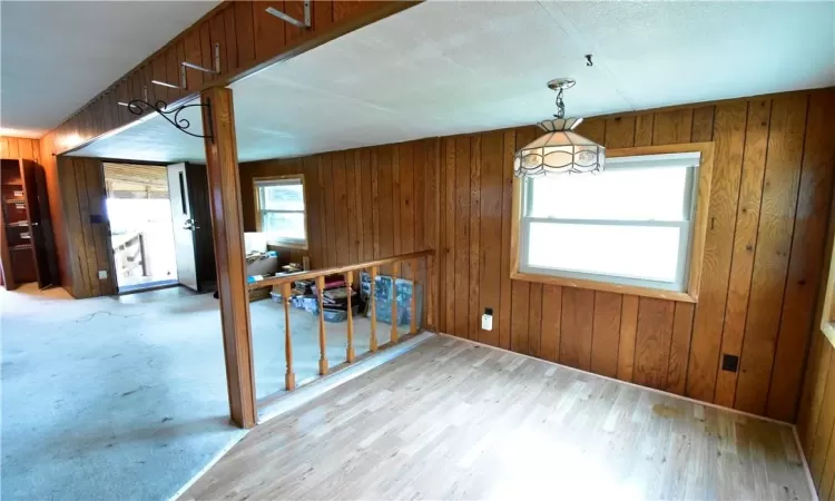 Unfurnished dining area with wooden walls and light wood-type flooring