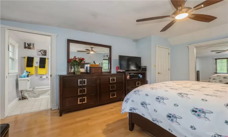 Bedroom with ensuite bathroom, light wood-type flooring, and ceiling fan