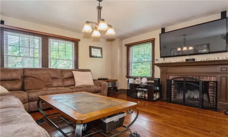 Living room featuring dark hardwood / wood-style floors, a notable chandelier, and a fireplace