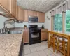 Kitchen featuring light tile floors, sink, a wealth of natural light, and black range with gas cooktop