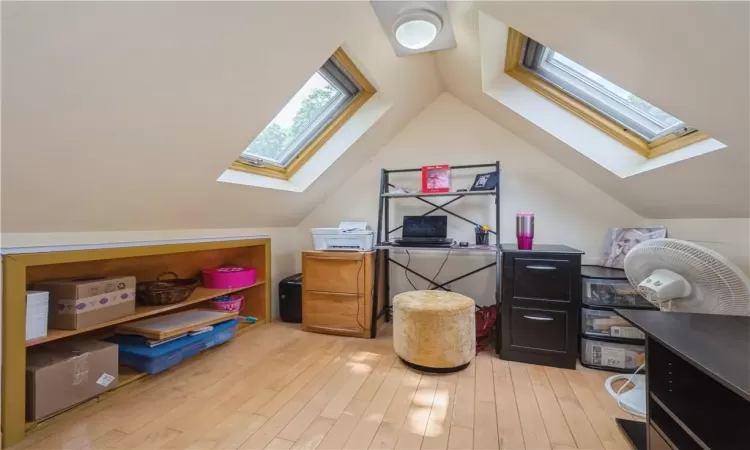 Office featuring light hardwood / wood-style flooring and lofted ceiling with skylight