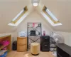 Office with light hardwood / wood-style floors and lofted ceiling with skylight