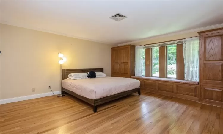 Bedroom with ornamental molding and light hardwood / wood-style floors