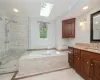 Bathroom with shower with separate bathtub, vanity, tile floors, and a skylight