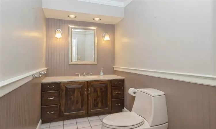 Bathroom featuring vanity, toilet, tile floors, and crown molding