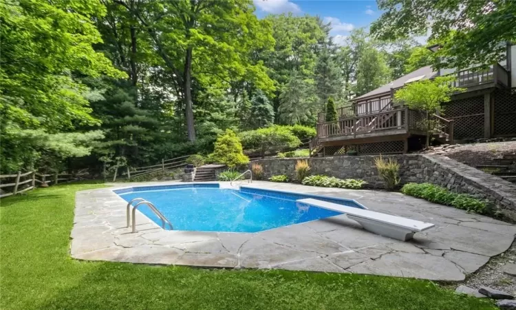 View of pool with a deck, a diving board, and a lawn