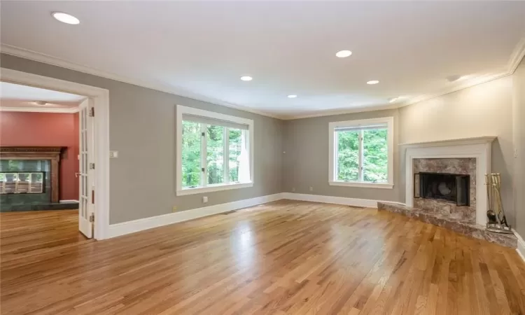 Unfurnished living room featuring crown molding, a fireplace, and light wood-type flooring