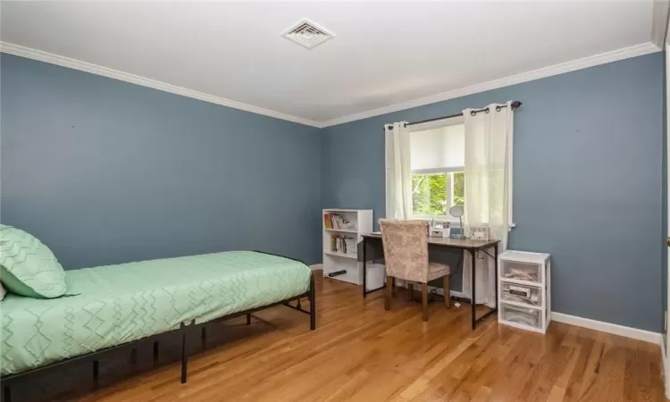 Bedroom with ornamental molding and hardwood / wood-style floors