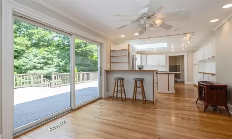 Kitchen featuring light hardwood / wood-style floors, kitchen peninsula, white cabinets, and a breakfast bar area