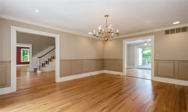 Empty room featuring a healthy amount of sunlight, ornamental molding, light hardwood / wood-style floors, and ceiling fan with notable chandelier