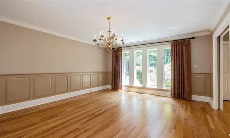 Spare room featuring a notable chandelier, ornamental molding, and light hardwood / wood-style flooring