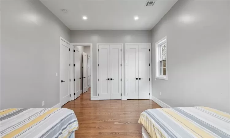 Bedroom with multiple closets and hardwood / wood-style floors