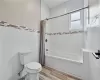 Bathroom with tile floors, toilet, shower / bath combo with shower curtain, and tile walls