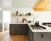 Kitchen with sink, stainless steel gas stovetop, light stone counters, and light hardwood / wood-style flooring