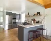 Kitchen with crown molding, kitchen peninsula, light wood-type flooring, light stone counters, and appliances with stainless steel finishes