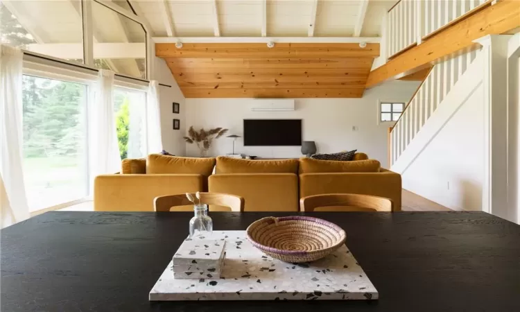 Dining room with beamed ceiling, wooden ceiling, hardwood / wood-style floors, a wall mounted air conditioner, and high vaulted ceiling