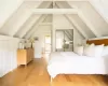 Bedroom with lofted ceiling with beams, light hardwood / wood-style floors, and a closet