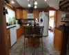 Kitchen with an inviting chandelier, vaulted ceiling, a kitchen island, tasteful backsplash, and white appliances