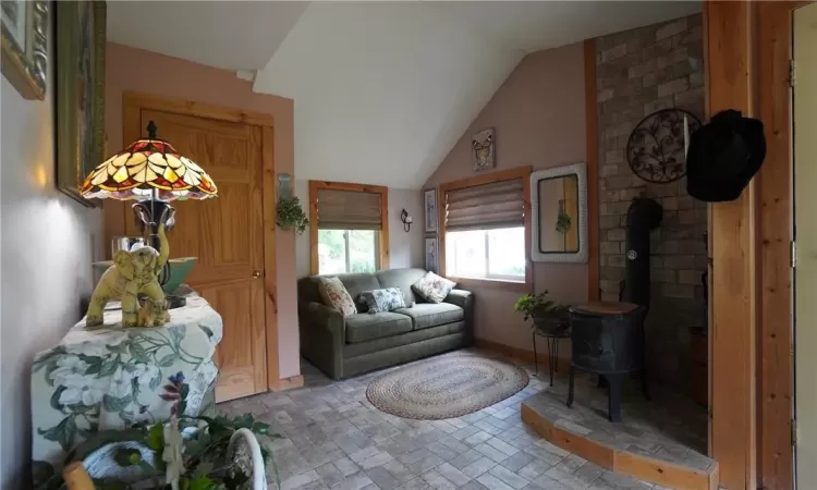 bedroom with brick wall, a wood stove, and lofted ceiling