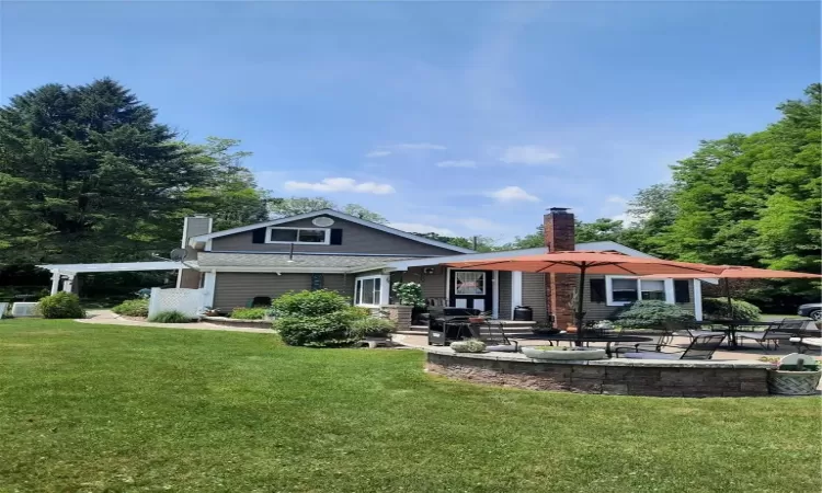 Rear view of house featuring a yard, a pergola, and a patio