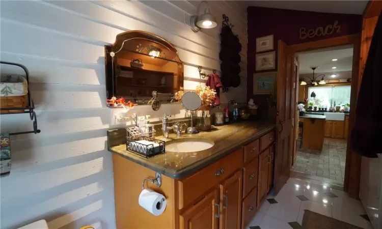 Bathroom with vaulted ceiling, tile flooring, a chandelier, and large vanity