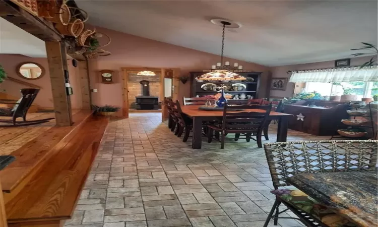 Dining space featuring vaulted ceiling, a wood stove, and a chandelier