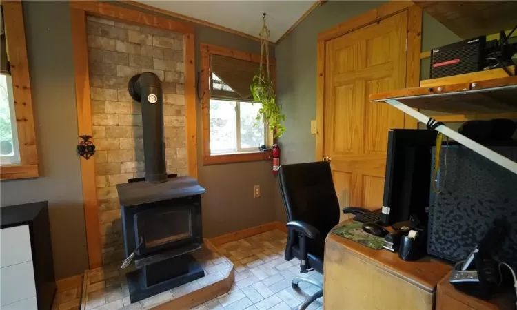 bedroom/home office featuring lofted ceiling and a wood stove