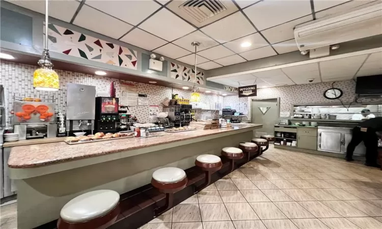 Kitchen with tile floors, a kitchen bar, pendant lighting, and a drop ceiling