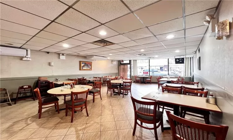 Dining space featuring light tile flooring, a paneled ceiling, and a wall mounted AC