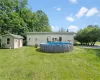 Rear view of property with an outdoor structure and a yard