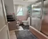 Bathroom featuring tile walls, tile floors, shower / bath combination with glass door, and toilet