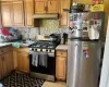 Kitchen with stainless steel fridge, tasteful backsplash, gas range oven, light tile floors, and tile countertops