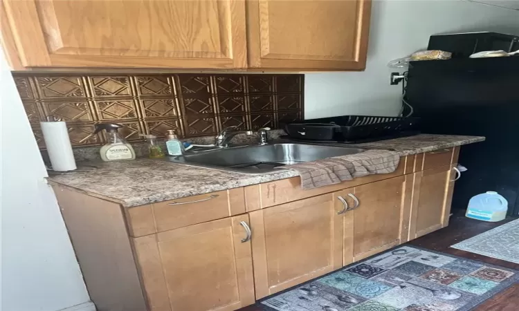 Kitchen with dark wood-type flooring, sink, and tasteful backsplash