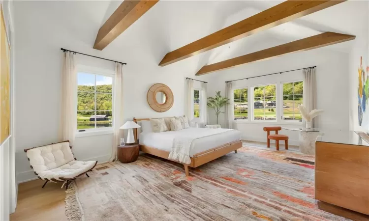 Bedroom with multiple windows, vaulted ceiling with beams, and hardwood / wood-style flooring