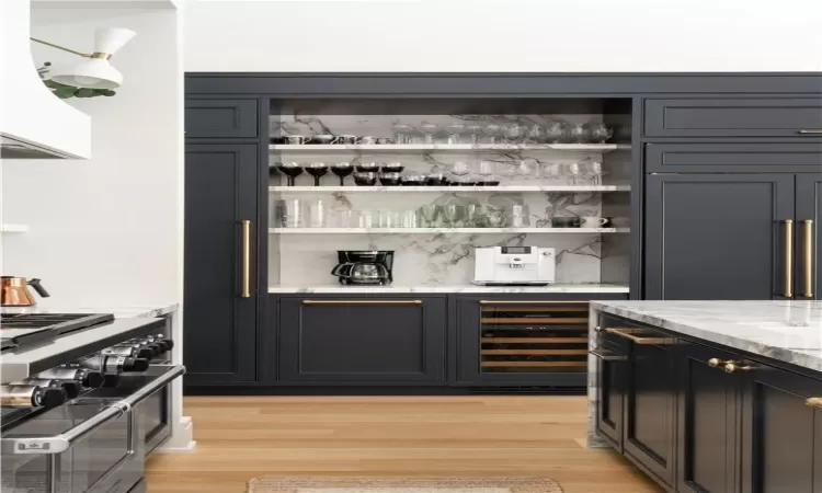 Bar featuring light stone countertops, light wood-type flooring, range, and wine cooler