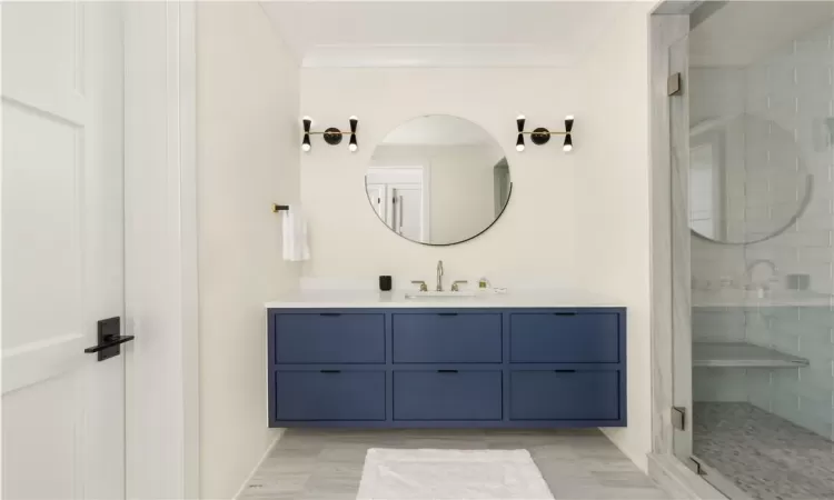 Bathroom featuring vanity, crown molding, and a shower with door