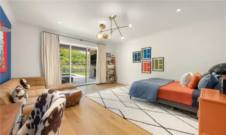 Bedroom with crown molding, an inviting chandelier, light hardwood / wood-style flooring, and access to exterior