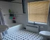 Bathroom with tile floors, tile walls, toilet, and radiator