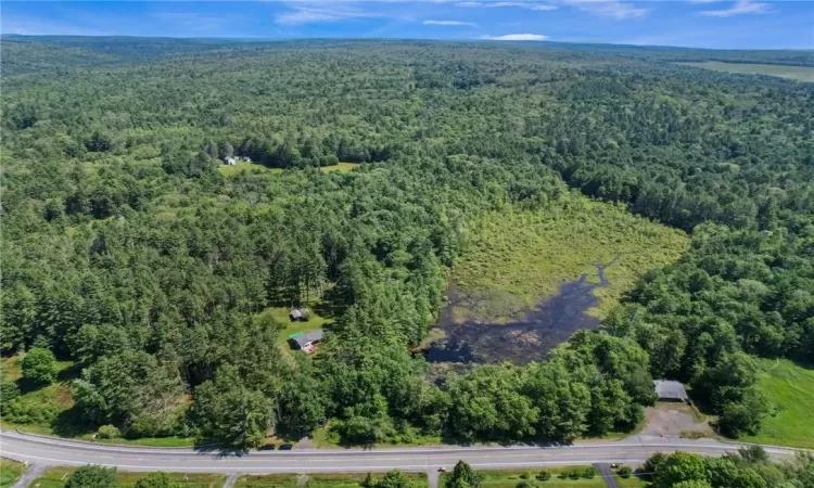 Aerial View of total property with home, pond and front of 