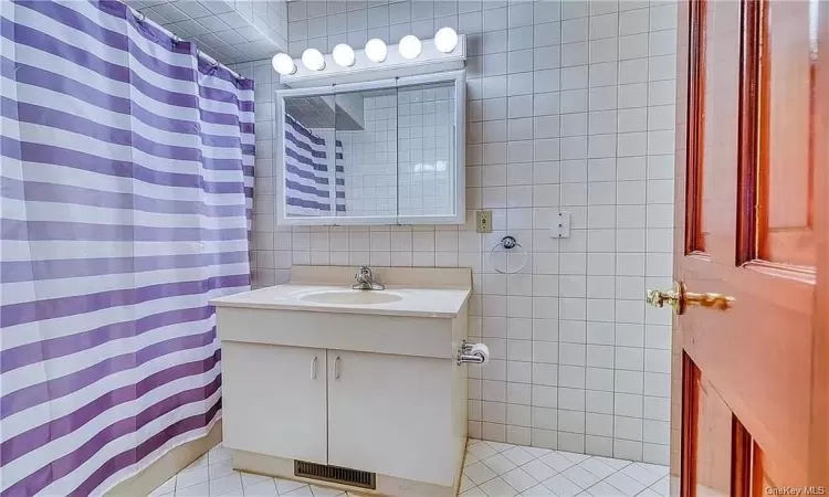 Bathroom with tile walls, tile floors, and vanity