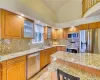 Kitchen with light stone counters, appliances with stainless steel finishes, tasteful backsplash, and light hardwood / wood-style flooring