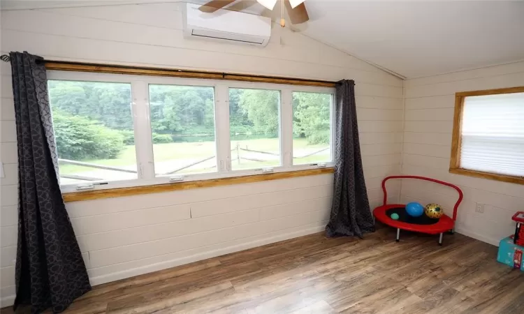 Second bedroom with a mini-split unit, dark wood-type flooring, ceiling fan, and lofted ceiling