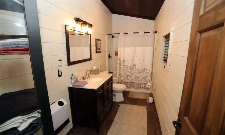 Bathroom with wooden walls, hardwood / wood-style flooring, toilet, and vanity