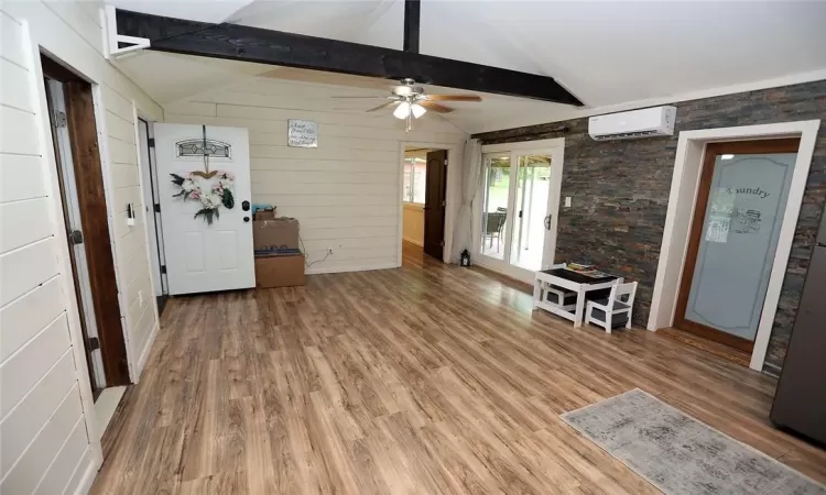 Unfurnished dining area with lofted ceiling with beams, ceiling fan, a wall mounted air conditioner, and hardwood / wood-style floors