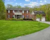 Colonial-style house with a front yard, a garage, and a balcony