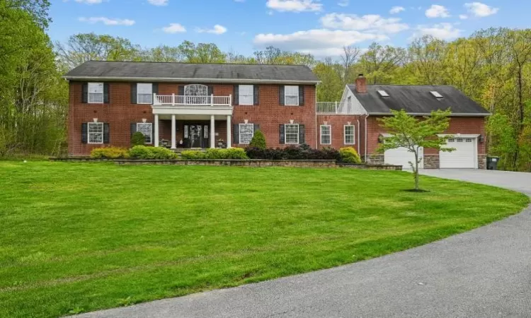 Colonial-style house with a front yard, a garage, and a balcony